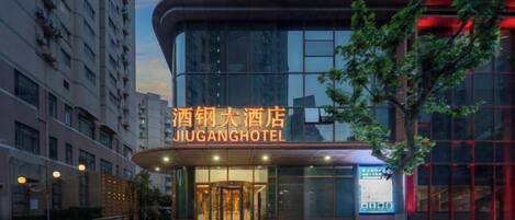 Un hotel con fachada moderna, señalización iluminada y acceso de vidrio.