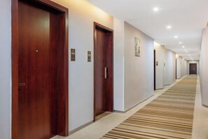 A hotel corridor with wooden doors, a carpeted floor, and a long hallway. - Jiugang Hotel (Shanghai)