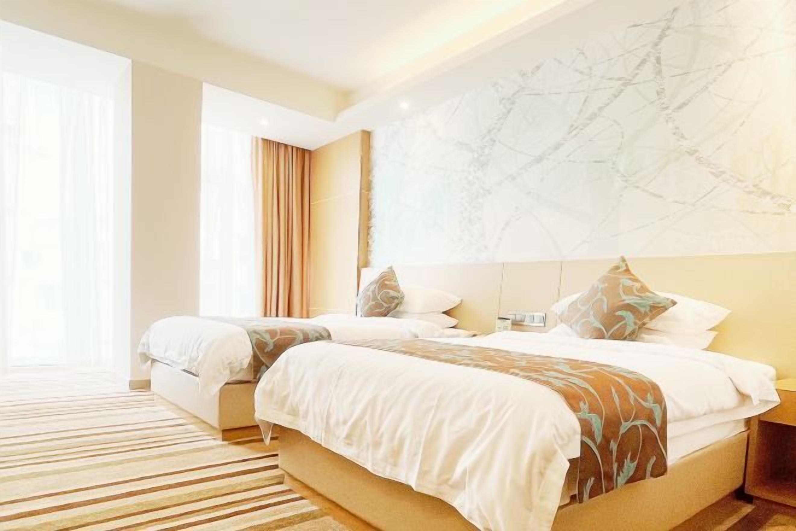 Een hotelkamer met twee bedden, een marmeren wand en een groot raam met gordijnen.