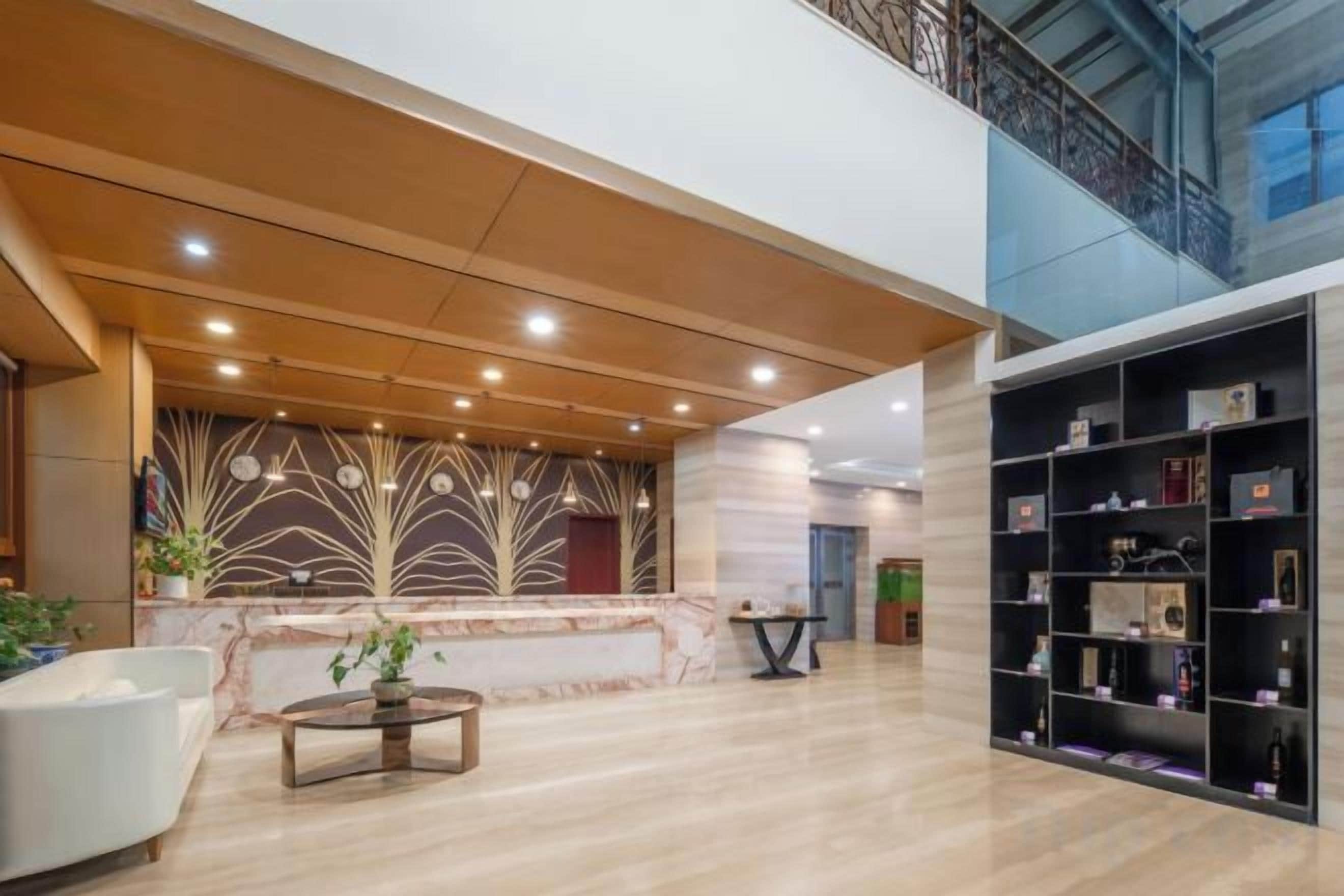 A spacious lobby with a reception desk, seating area, and a bookshelf.