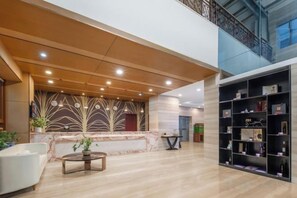 A spacious lobby with a reception desk, seating area, and a bookshelf. - Jiugang Hotel (Shanghai)