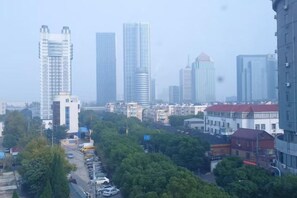A cityscape with multiple high-rise buildings, a tree-lined street, and parked vehicles.
