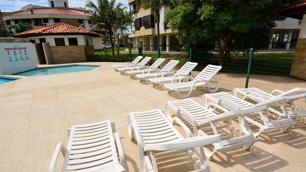 A poolside area with multiple white lounge chairs arranged in rows.