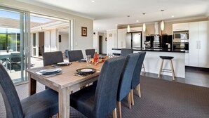 A modern kitchen with a dining area, large windows, and a view of the outdoors. - Delight in the Dell - 2 mins to lake (Taupō)
