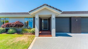 A modern two-story house with a front porch, a garage, and a well-maintained lawn. - Delight in the Dell - 2 mins to lake (Taupō)