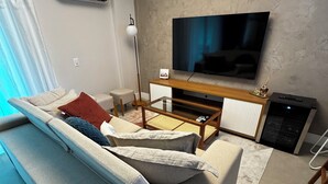 Een moderne woonkamer met een bank, een televisie en een airconditioner.