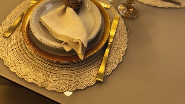 Een gedekte tafel met goudkleurig servies, glazen en bestek.