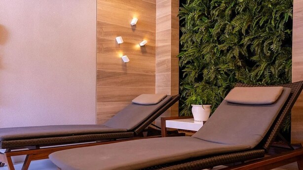 A spa area with two lounge chairs, a wall-mounted light fixture, and a vertical garden. - Solar Tambaú - LikeHome Hospedagens (Joao Pessoa)