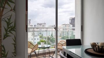Een balkon met rieten stoelen, een klein tafeltje en een bloempot.