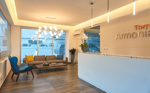 A modern reception area with a reception desk, a chandelier, a sofa, and a coffee table. - Torre Armonia 24 (Santo Domingo)