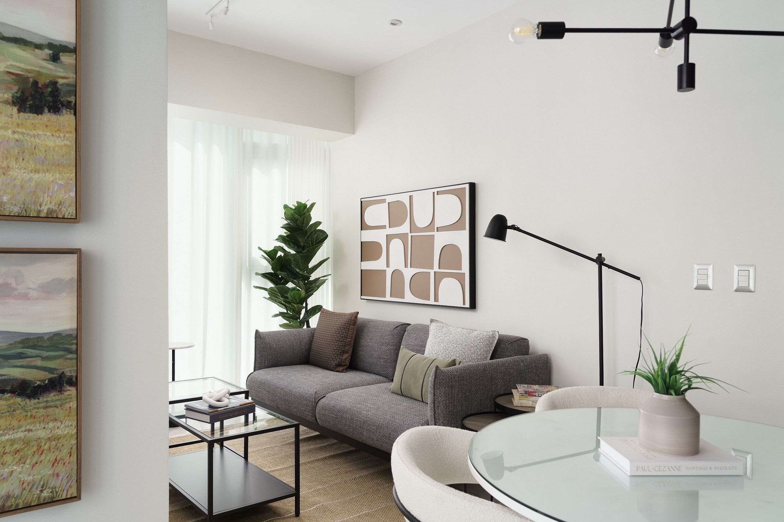 Un salon moderne avec un canapé gris, une table basse en verre et une plante en pot.