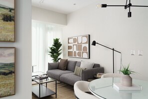 A modern living room with a grey sofa, a glass coffee table, and a potted plant. - Torre Armonia 24 (Santo Domingo)