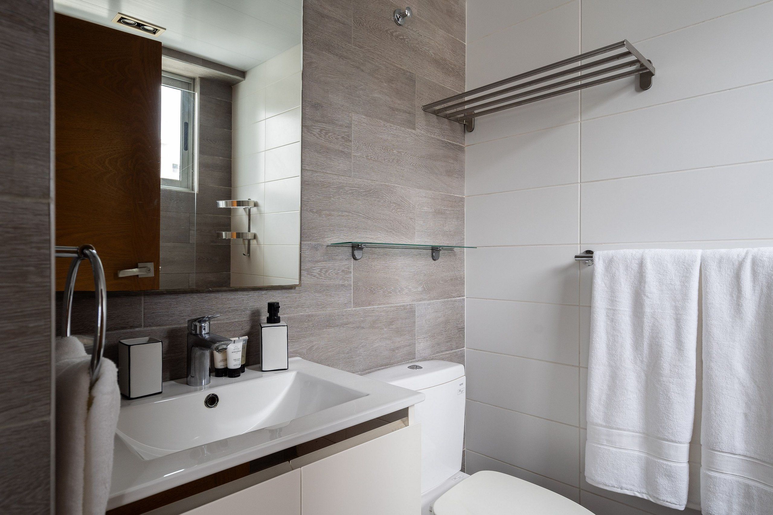 A modern bathroom with a white sink, mirror, and toilet.