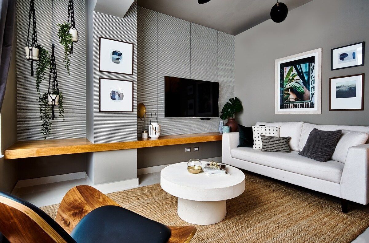 Ein modernes Wohnzimmer mit einem weißen Sofa, einem runden Couchtisch und einem an der Wand befestigten Fernseher.