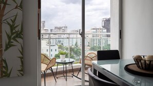 A balcony with wicker chairs, a small table, and a potted plant. - Torre Armonia 24 (Santo Domingo)