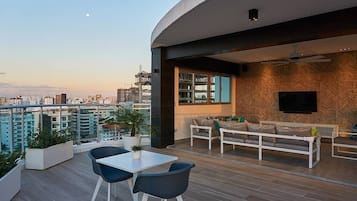 A modern apartment with a balcony, a dining area, and a living room with a TV.