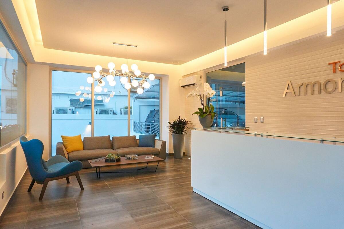 A modern reception area with a sofa, chairs, a coffee table, and a chandelier.
