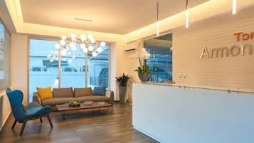 A modern reception area with a sofa, chairs, a coffee table, and a chandelier.