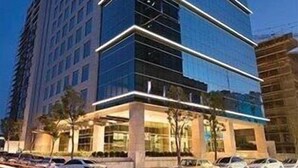A modern high-rise building with a glass facade and a prominent corner entrance. - Torre Armonia 24 (Santo Domingo)