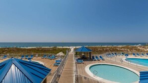 A pool area with a wooden deck, lounge chairs, and a gazebo.
