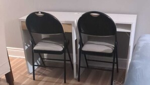 A room with a wooden floor, two black chairs, a white desk, and a blue bed. - Main Floor Unit (Richmond Hill)