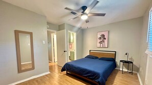 A bedroom with a bed, a ceiling fan, a framed mirror, and a door leading to another room. - Chic 2-bedroom apartment with WiFi, AC in enchanting Arlington (Arlington)