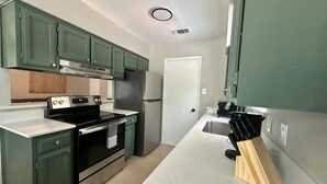 A compact kitchen with green cabinets, a stainless steel stove, and a countertop with a knife block. - Chic 2-bedroom apartment with WiFi, AC in enchanting Arlington (Arlington)