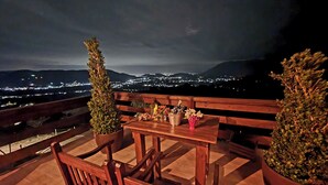 A wooden table and chairs on a balcony with a view of a cityscape at night. - Chale da Montanha (Santo Amaro da Imperatriz)