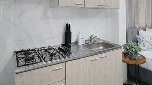 Une cuisine moderne avec des meubles en bois clair, une cuisinière à gaz et un dosseret en marbre.