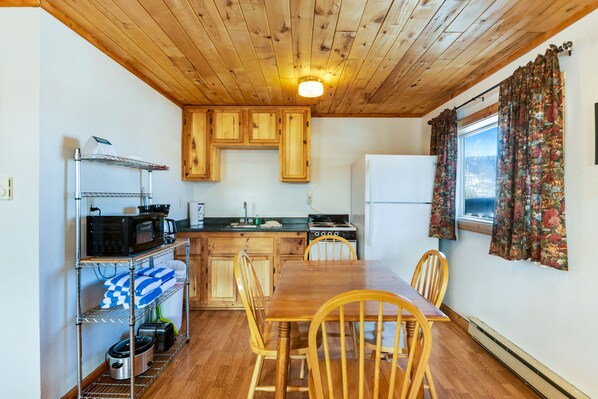 Une cuisine compacte avec des meubles en bois, une table à manger avec des chaises, un four à micro-ondes et une cuisinière.