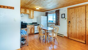 A wooden-paneled kitchen with a dining table and chairs, a refrigerator, and wooden cabinets.