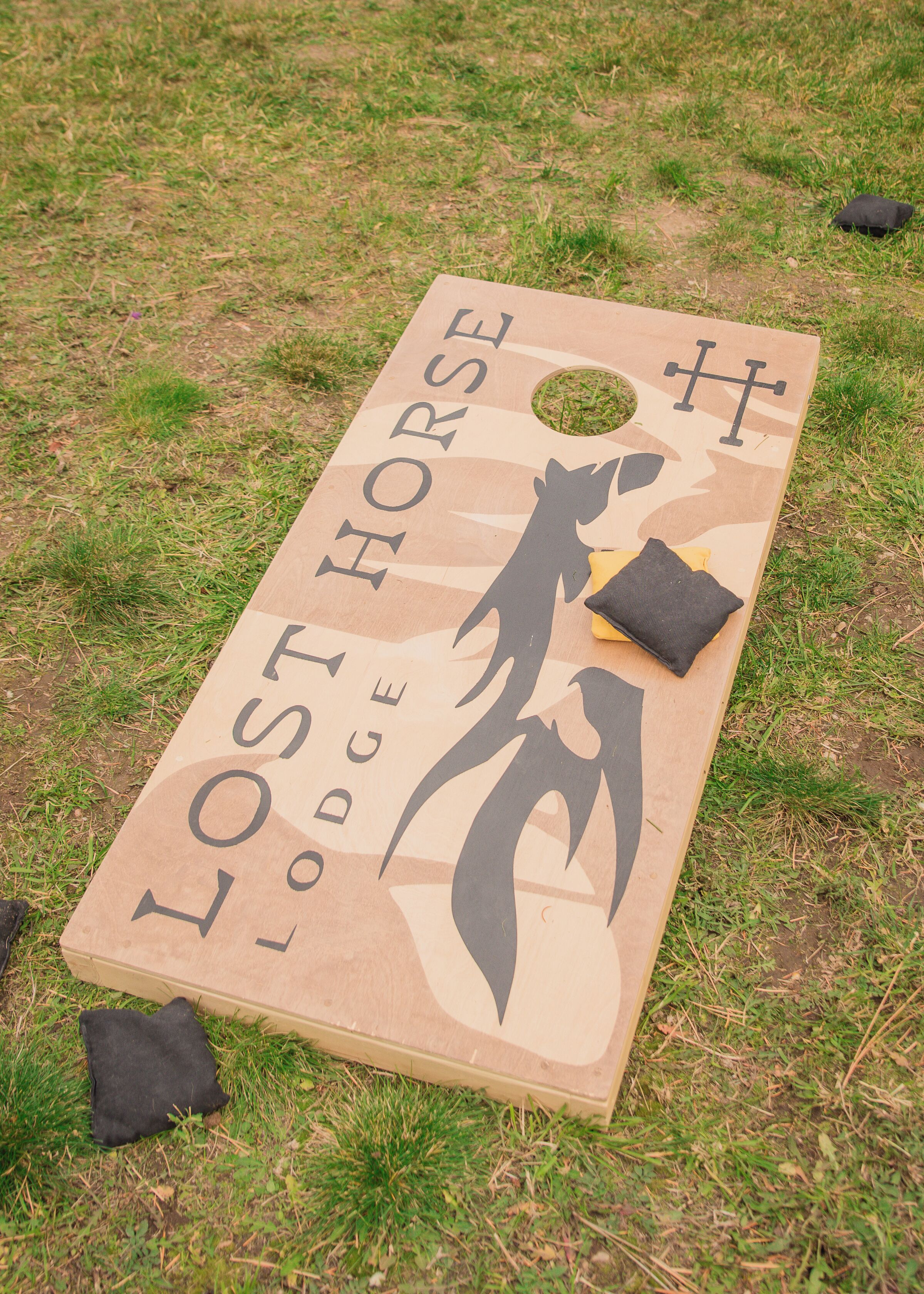 A wooden board game titled "Lost Horse Lodge" on grass.