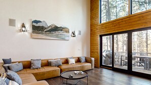Een moderne woonkamer met een hoekbank, een ronde salontafel en een groot raam met uitzicht op een terras.