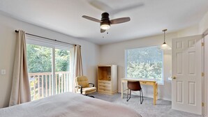 A bedroom with a bed, a desk, a chair, a wardrobe, a ceiling fan, and a window with a view of greenery. - Whale's Spout - Pet Friendly-Depoe Bay, OR (Depoe Bay)