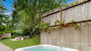 A hot tub in a backyard with a wooden fence, a grassy lawn, and a concrete wall. - Whale's Spout - Pet Friendly-Depoe Bay, OR (Depoe Bay)