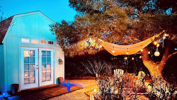 A blue house with a wooden deck and a hammock under string lights. - Stunning 3-Bed/2-Bath Villa with Hot Tub, Pool, & Garden in Joshua Tree (Joshua Tree)