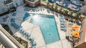 An aerial view of a hotel courtyard with a swimming pool, lounge chairs, and outdoor seating.