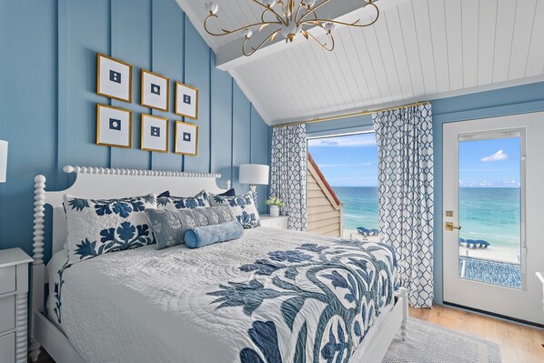 Un dormitorio con una cama grande, vista al océano y una escalera que lleva a un balcón.