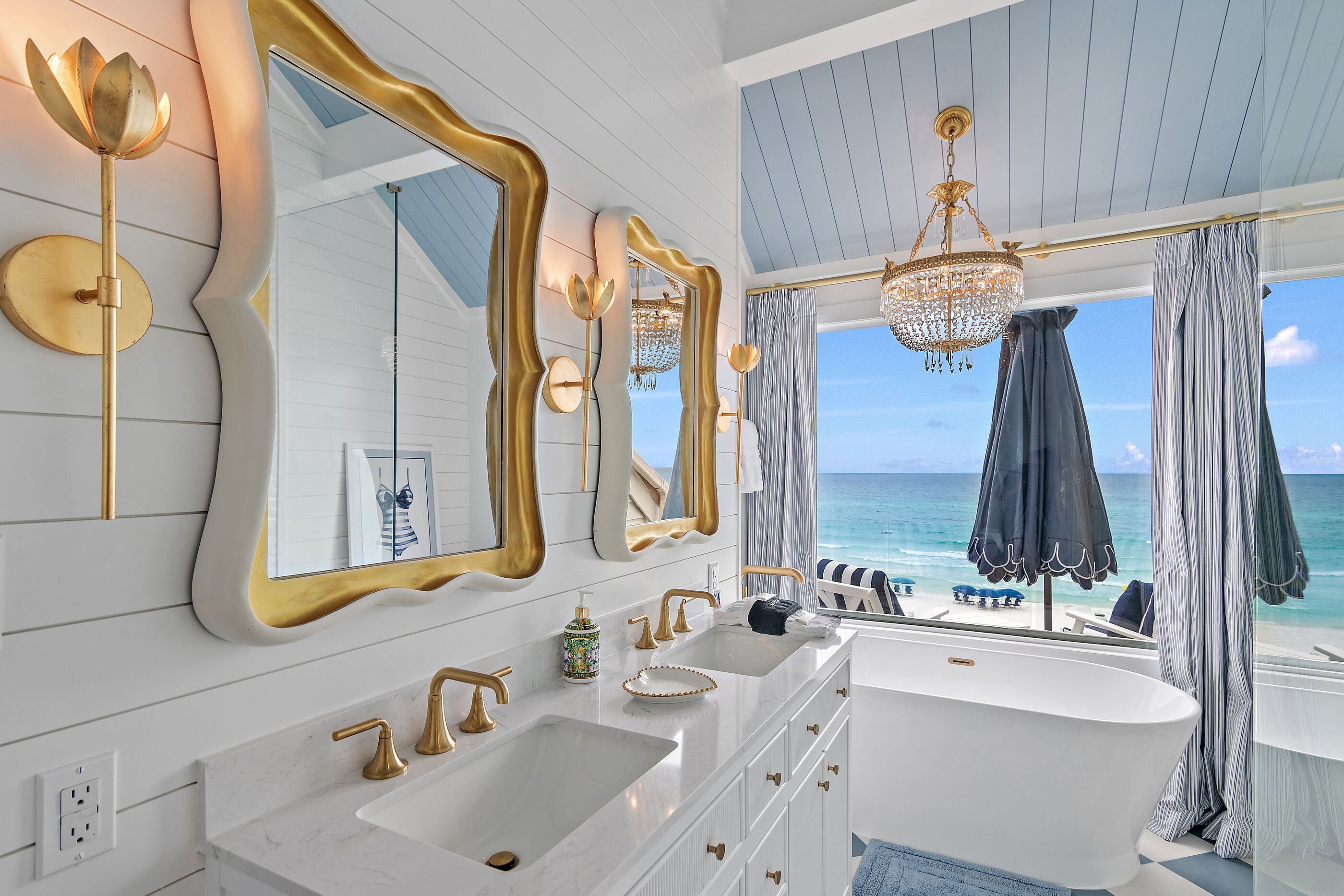 A bathroom with a large bathtub, two sinks, and a vanity with gold fixtures.