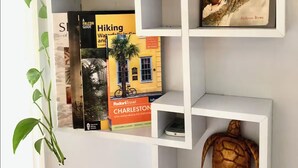 Une étagère blanche contenant des livres et une tortue décorative.