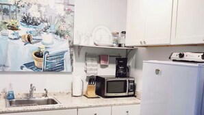 Une cuisine avec des meubles blancs, un évier, un four à micro-ondes et un réfrigérateur.