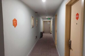 A hotel corridor with doors marked by orange signs, a trash bin, and a light switch on the wall. - 99 Inn Shanghai Guoquan Road Station (Shanghai)