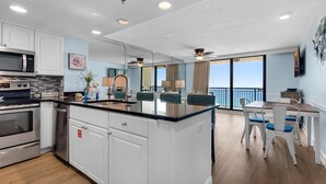A modern kitchen with stainless steel appliances, a central island, and a dining area with a view. - Sundestin 1403 (Destin)