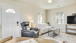Une pièce comprenant un lit, un fauteuil en cuir, une petite table, un téléviseur et un ventilateur de plafond.