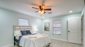 A bedroom with a bed, ceiling fan, and two windows. - Vibrant Tampa Home: Perfect for Long Stays! (Lutz)