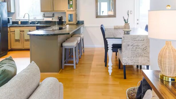 Una cucina moderna con isola centrale, sgabelli da bar e un tavolo da pranzo con sedie.