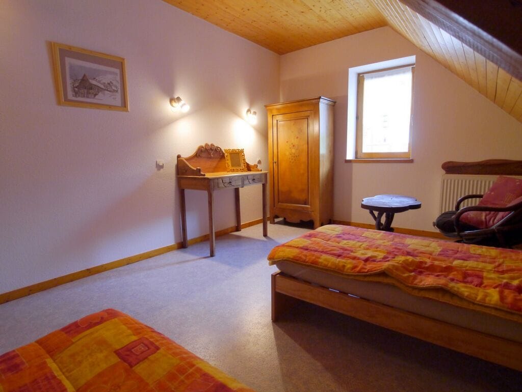 A bedroom with a bed, a desk, a chair, a radiator, and a window.