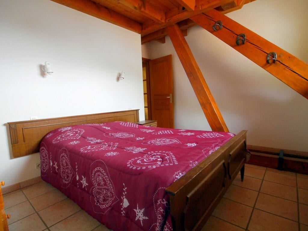 Un dormitorio con una cama de madera, techo inclinado y una puerta de madera.