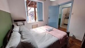 A bedroom with a bed, a window, a door, and a small table.