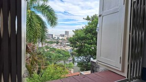 A balcony with a view of a cityscape, including buildings and greenery.